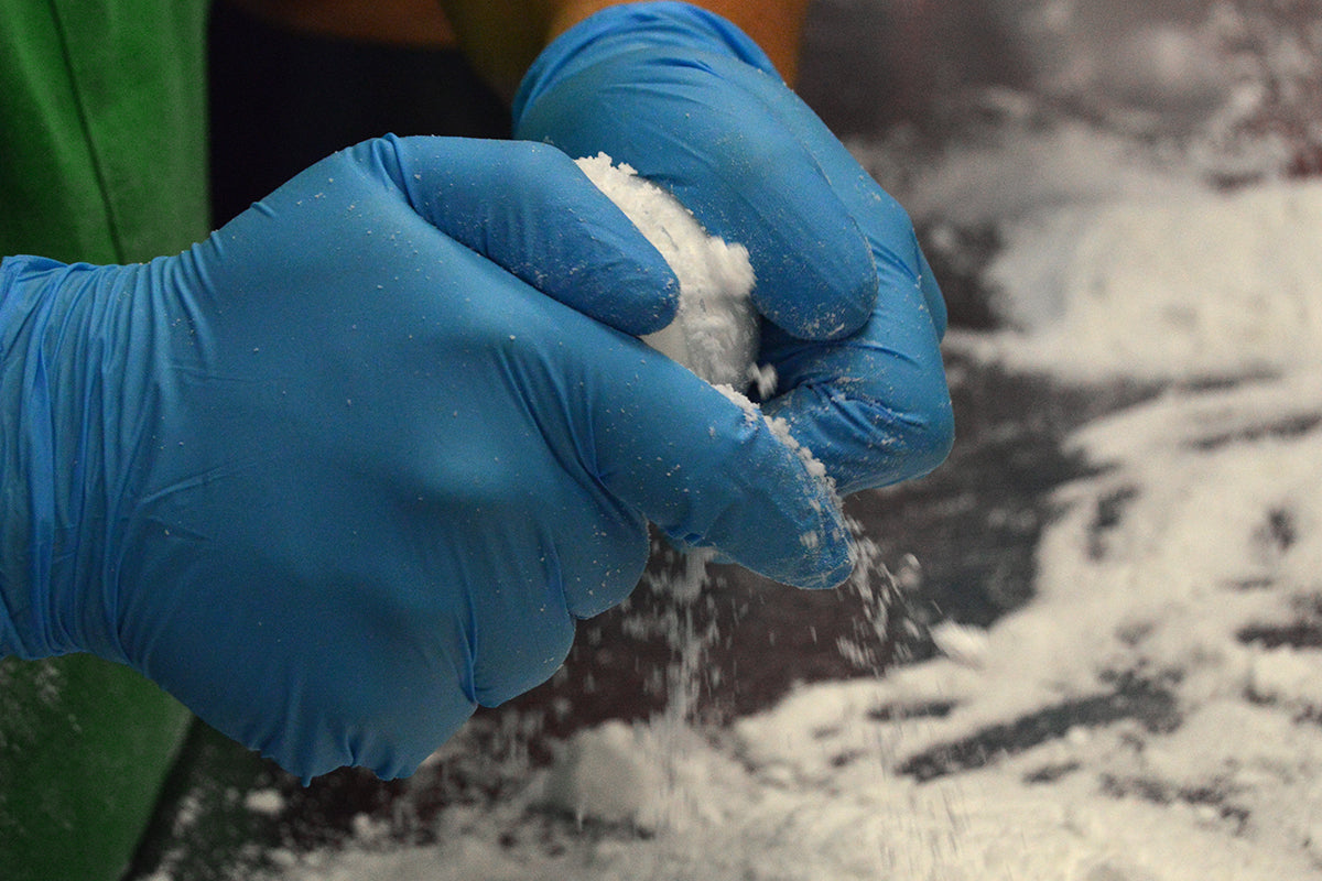Gloved hands pressing bath bomb mixture during production