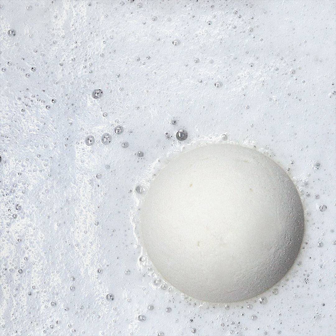 White Muscle Rehab bath bomb fizzing in water, surrounded by foamy bubbles and effervescent texture, creating a soothing and refreshing bath experience.