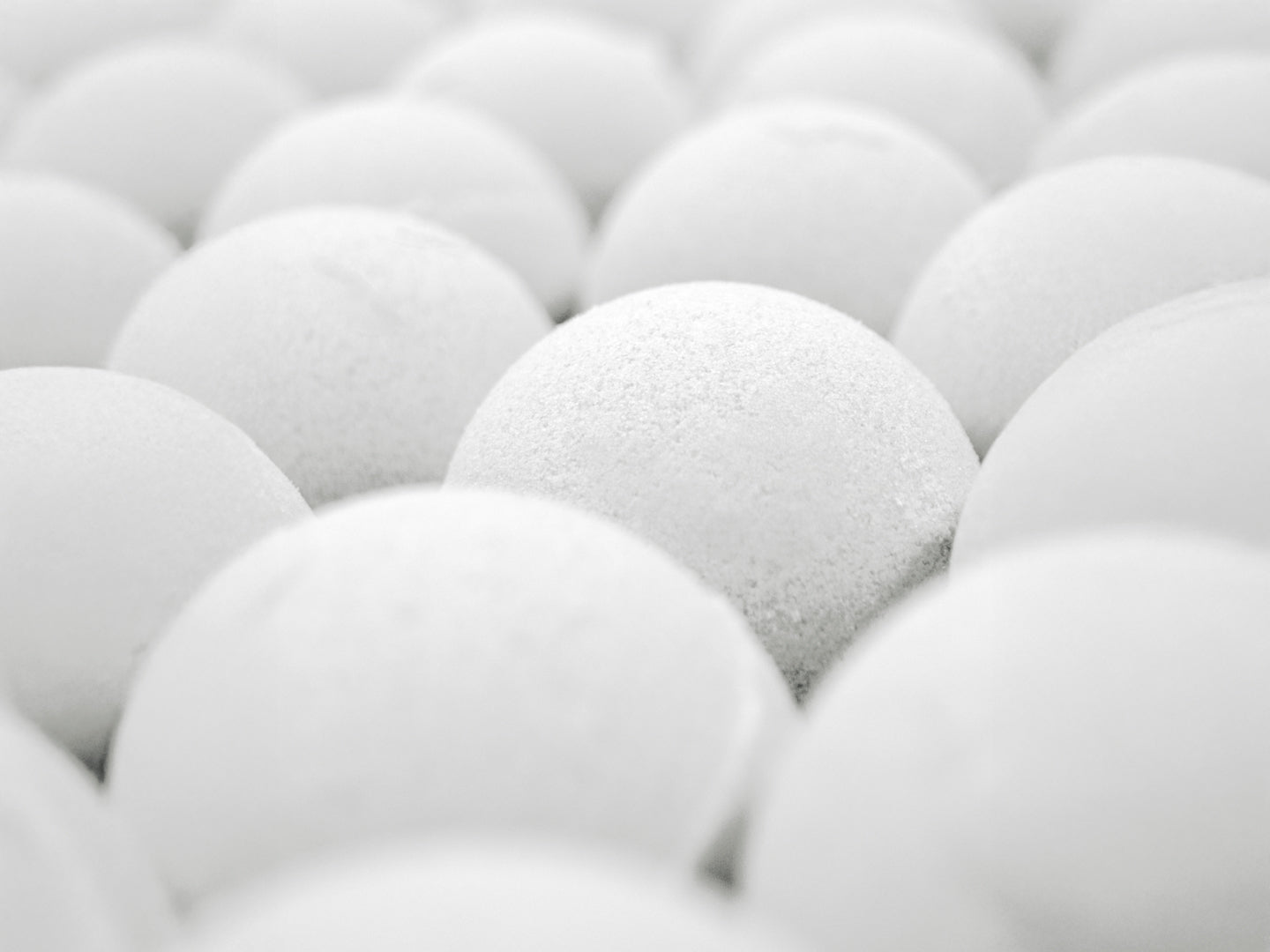 Close-up view of multiple white Muscle Rehab bath bombs arranged in a tray, highlighting their smooth, rounded texture and clean, minimalist appearance.