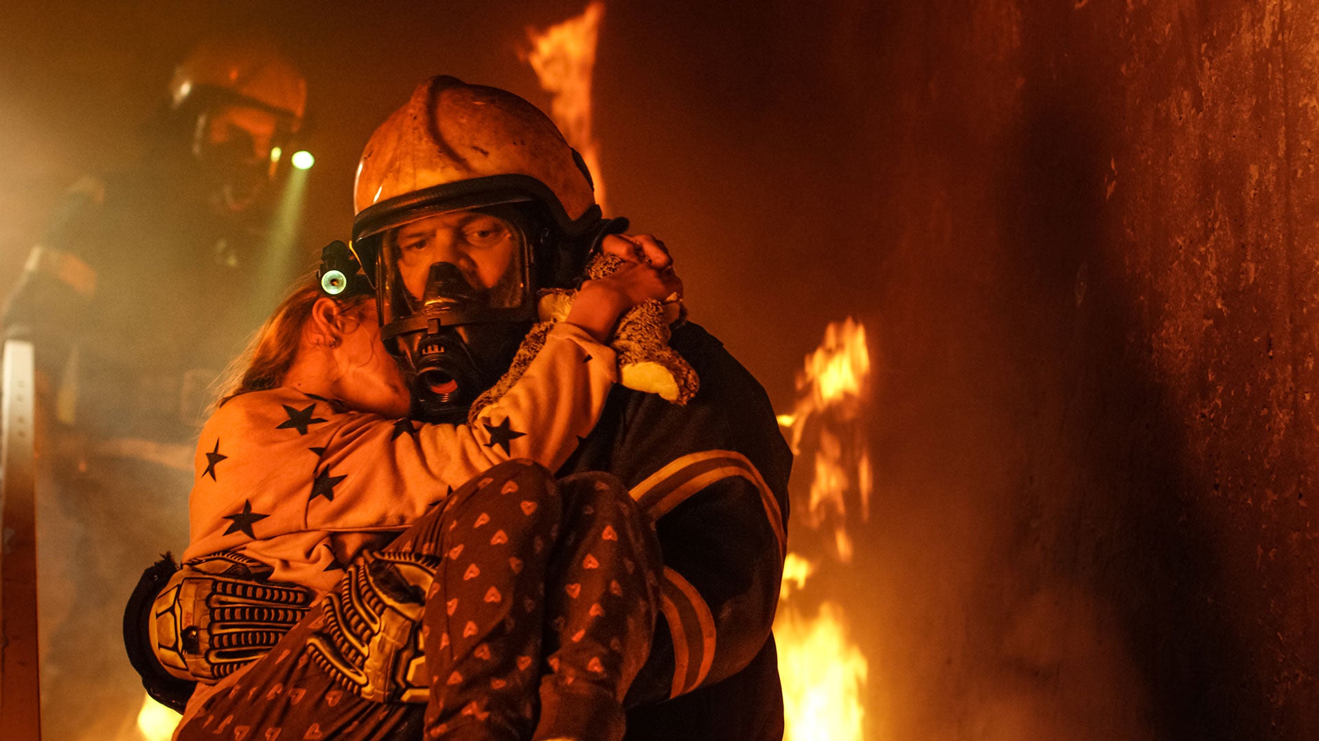 Firefighter in action with flames in the background