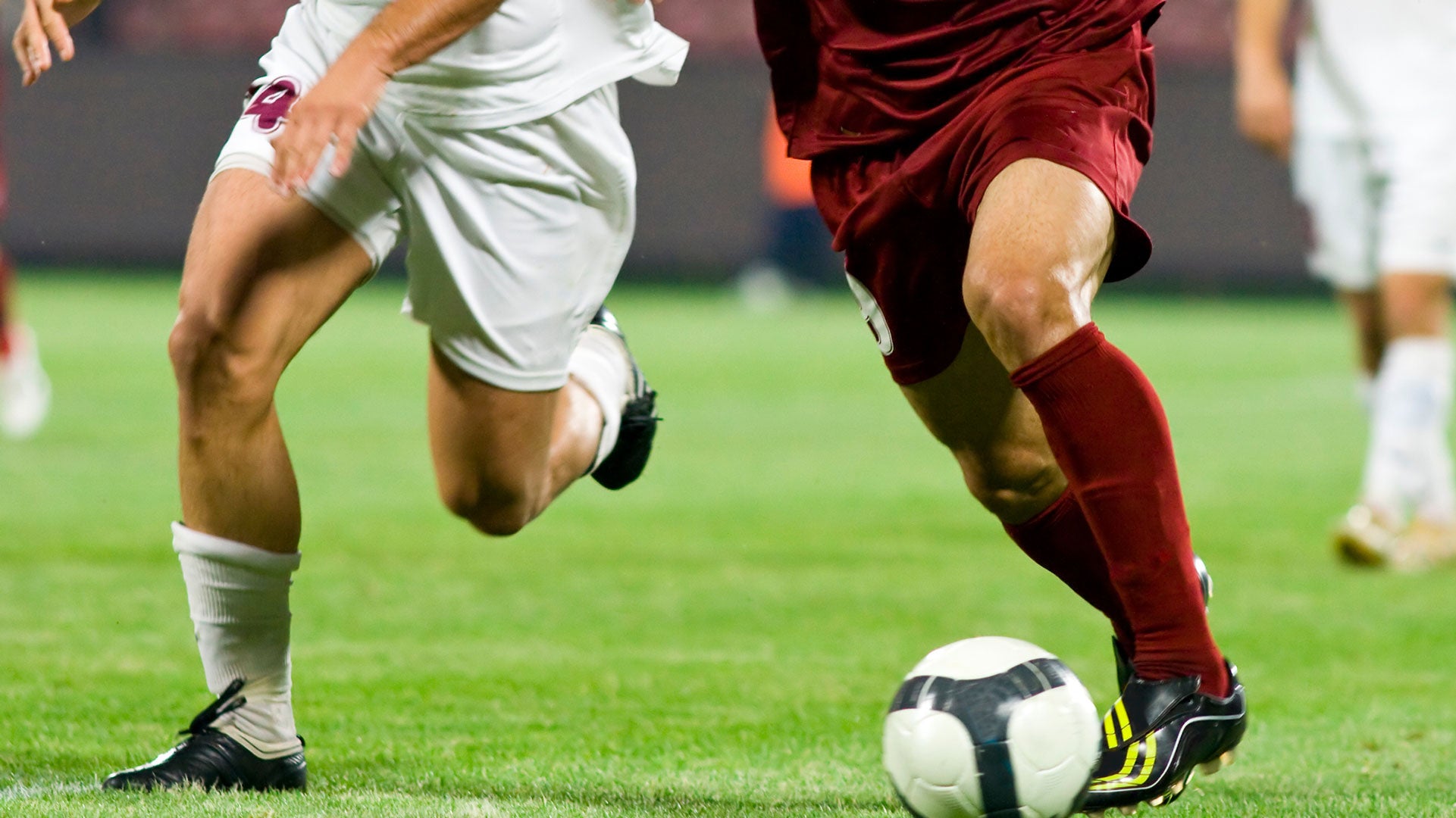 Two soccer players in action on a field with a ball