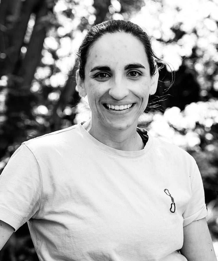 Black and white portrait of Lindsay Purcell smiling outdoors, part of the Muscle Rehab team.