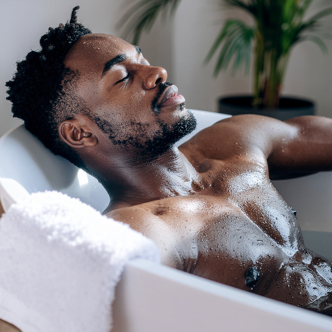 Man relaxing in a bath, symbolizing muscle recovery, relaxation, and post-workout self-care.
