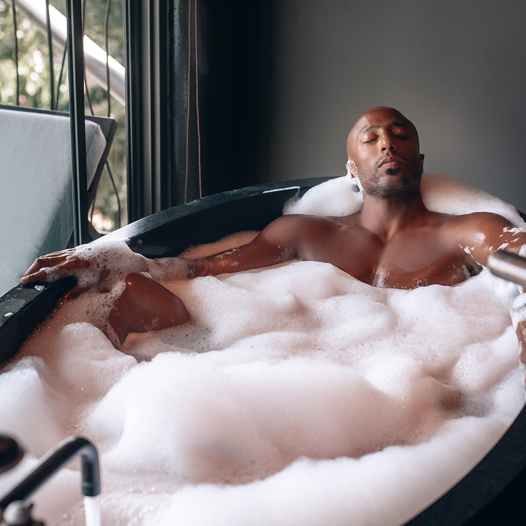 Man relaxing in a warm Muscle Rehab bath, symbolizing heat therapy, recovery, and stress relief.