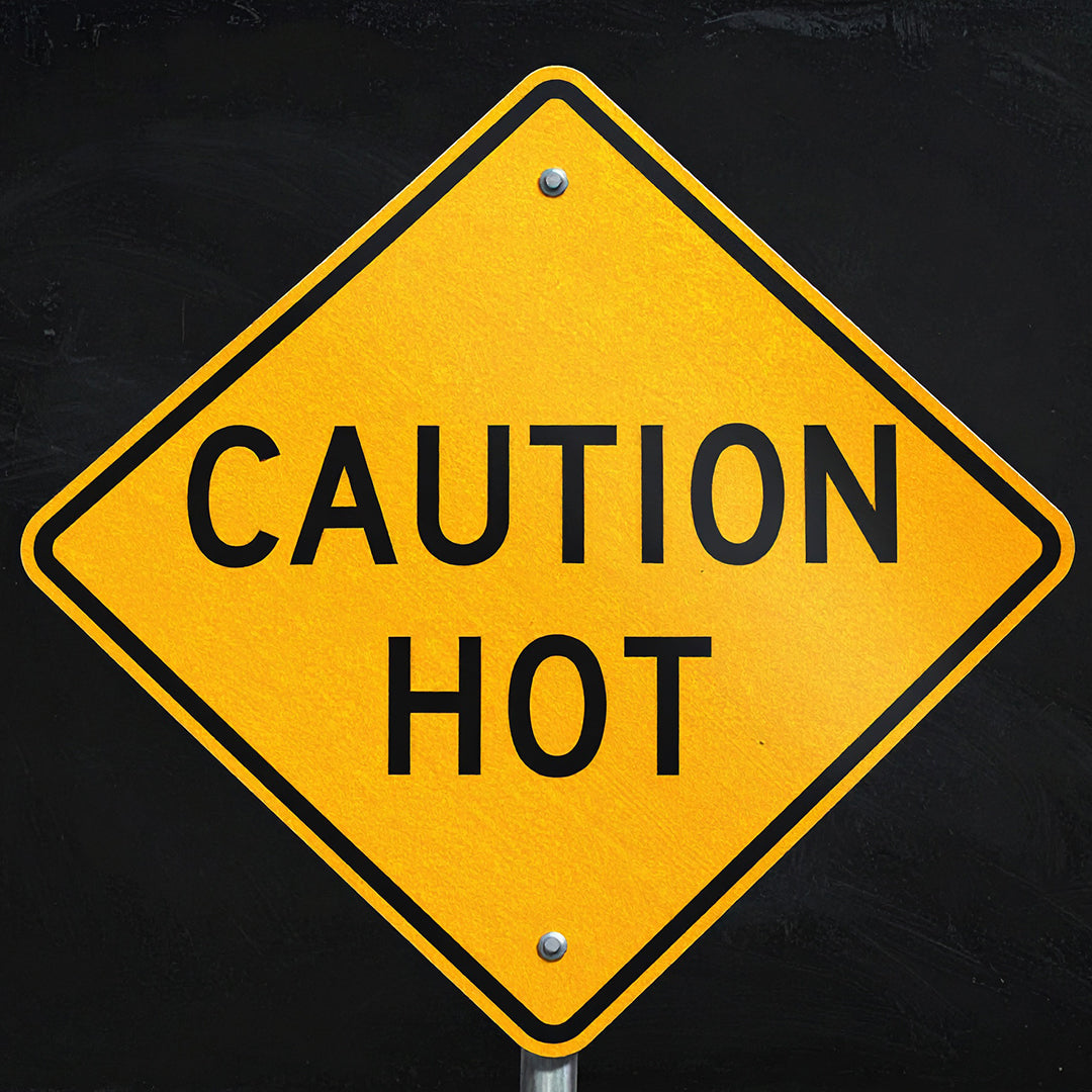 Yellow diamond road sign with the words “Caution Hot” in black, symbolizing heat warning or therapy.